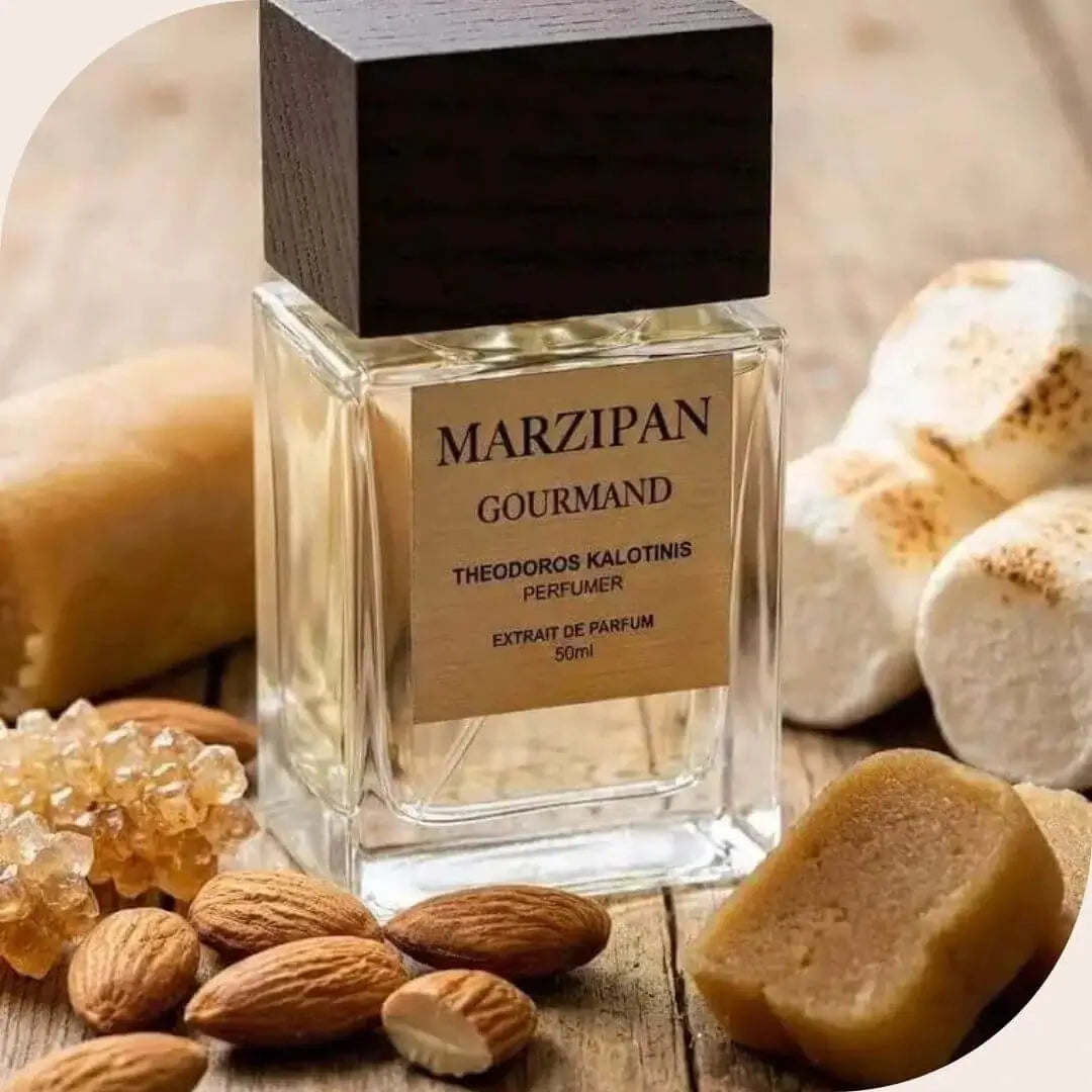 Marzipan Gourmand by Theodoros Kalotinis perfume bottle displayed with key ingredients including almonds, marzipan chunks, and toasted marshmallows on a wooden surface.